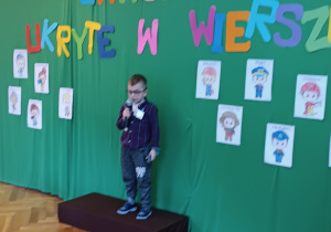 Chłopiec stoi na scenie trzymając w rękach mikrofon