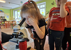 Dziewczynka spogląda w mikroskop