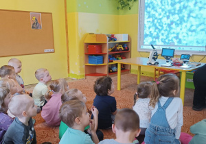 .Dzieci obserwują tablicę interaktywną, na której wyświetlany jest obraz z mikroskopu