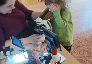 Dziewczynka patrzy przez mikroskop