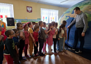 Dzieci ustawione "w pociąg" wchodzą do planetarium