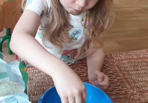 dziewczynka wsypuje ryż do wody zabarwionej bibułą