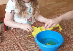 dziewczynka przygotowuje bibułę do zabarwienia wody