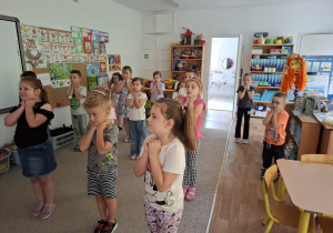 Dzieci naśladują ruchy wykonywane przez prowadzącą - przyjmują bezpieczną pozycję przy spotkaniu z psem