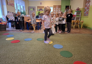 Dziewczynka przechodzi przez dywan stąpając wyłącznie po kropkach