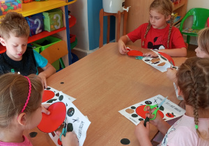 Dzieci wycinają jabłka siedząc przy stolikach