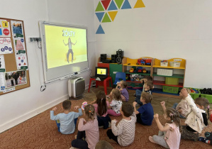Dzieci ćwiczą według wskazówek pokazanych na filmie