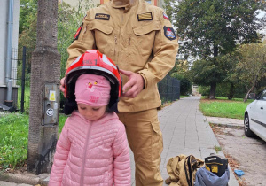 Dziewczynka pozuje w chełmie strażackim.