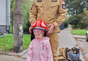 Dziewczynka pozuje w chełmie strażackim.