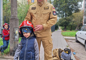 Chłopiec pozuje w chełmie strażackim.