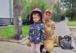 Dziewczynka pozuje w chełmie strażackim.