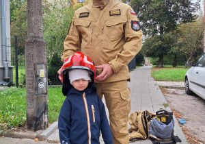 Chłopiec pozuje w chełmie strażackim.