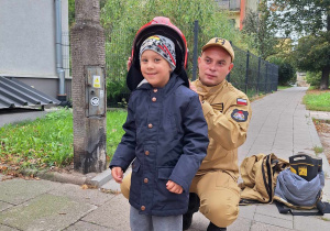 Chłopiec pozuje w chełmie strażackim.