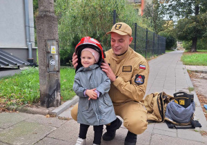 Dziewczynka pozuje w chełmie strażackim.