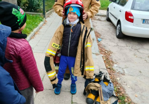 Dziecko pozuje do zdjęcia w ubiorze strażaka