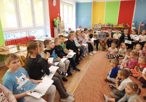 Uczniowie szkoły podstawowej czytają przedszkolakom swoje ulubione książki