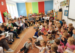 Uczniowie szkoły podstawowej czytają przedszkolakom swoje ulubione książki
