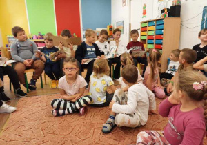 Uczniowie szkoły podstawowej czytają przedszkolakom swoje ulubione książki