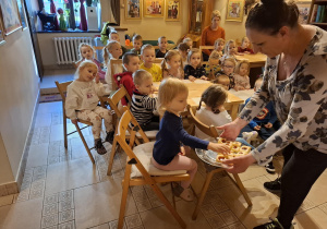 Pani częstuje dzieci ciastkiem