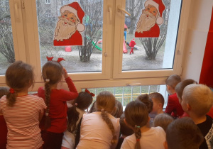 Dzieci obserwują Mikołaja spacerującego po ogrodzie przedszkolnym