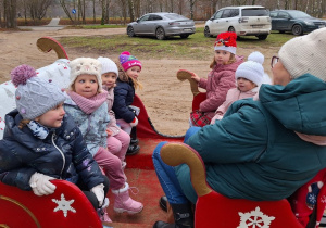 Grupa dzieci czeka w saniach na przejażdżkę.