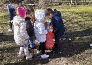 Chłopiec wkłada śmieci do worka trzymanego przez koleżankę