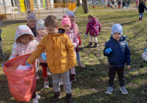 Chłopiec wkłada śmieci do worka trzymanego przez koleżankę