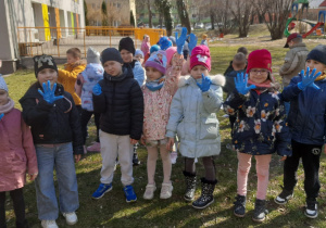 Dzieci pokazują założone na dłonie rękawiczki ochronne