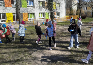 Grupa dzieci porządkuje ogród przedszkolny