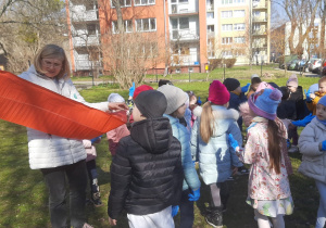 Nauczycielka rozdaje dzieciom worki na śmieci