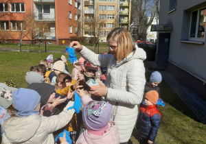 Nauczycielka rozdaje dzieciom rękawiczki ochronne