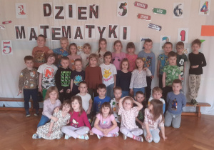 Dzieci pozują do zdjęcia na tle napisu Dzień Matematyki