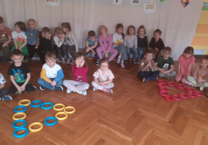 Dzieci siedzą w grupach przy trójkątach ułożonych z obręczy