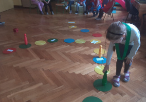Dziewczynka stawia zielony kręgiel na planszy