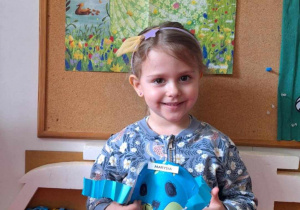 Dziewczynka pozuje do zdjęcia trzymając obrazek kuli ziemskiej