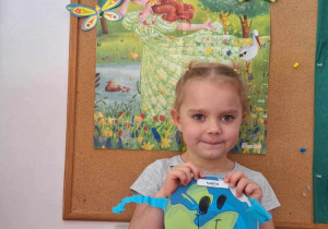 Dziewczynka pozuje do zdjęcia trzymając obrazek kuli ziemskiej