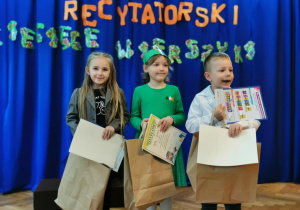 Trzyosobowy zespół dzieci z dyplomami i upominkami