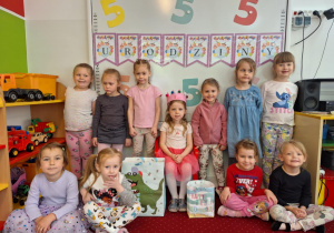 Dziewczynki siedzą na dywanie i pozują do zdjęcia z solenizantką
