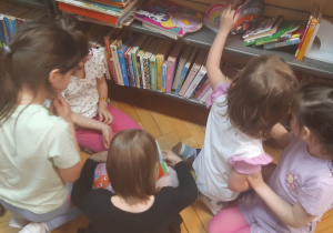 Dzieci oglądają książki na półkach w bibliotece