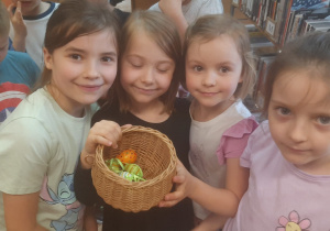 Dzieczynki pokazują w koszyku pisanki znalezione w bibliotece