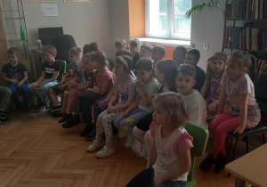 Dzieci słuchają opowiadanie czytanego przez bibliotekarkę