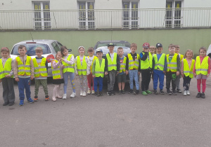Grupa dzieci pozuje do zdjęcia na tle budynku biblioteki