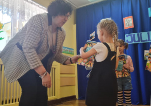 Dyrektorka wręcza dziecku nagrodę za udział w konkursie