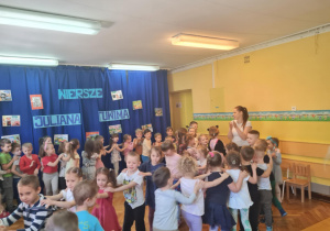 Dzieci uczestniczą we wspólnej zabawie wędrując po sali gimnastycznej ustawione "w pociąg"