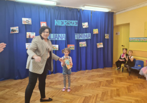 Dyrektorka wręcza dziecku nagrodę za udział w konkursie