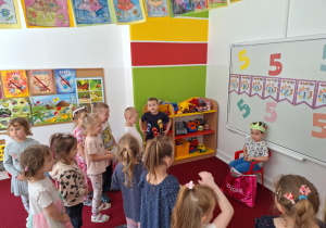 Dzieci stoią na dywanie i śpiewają sto lat solenizantowi