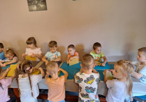 Dzieci siedzą przy stole i robią świeczkę