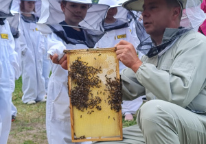Dziecko pozuje z ramką z pszczołami