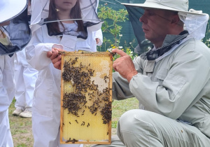 Dziecko pozuje z ramką z pszczołami