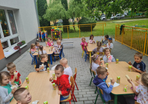 Dzieci jedzą podwieczorek na ogrodzie